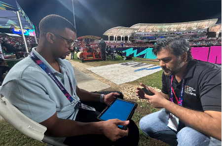 A young man shows a computer platform to another man outside