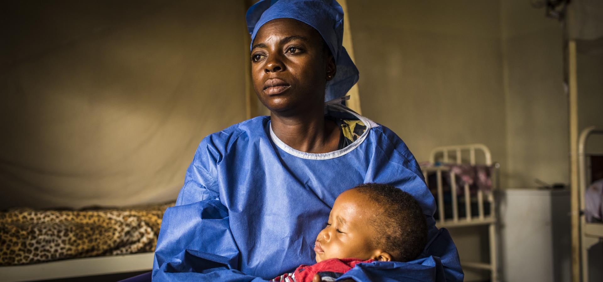 Health worker in scrubs holding a child