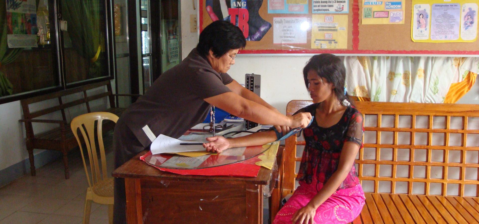 One woman puts a blood pressure cuff on another