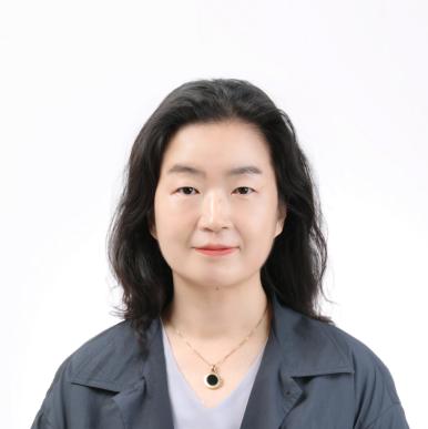 Woman wearing a gray blazer and shoulder length brown hair looks into the camera