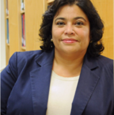 Honduran woman wearing a blue blazer, smiles into the camera