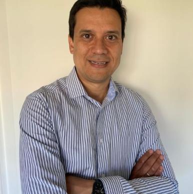 Javier Guzman Cruz headshot Man with crossed arms smiles into the camera