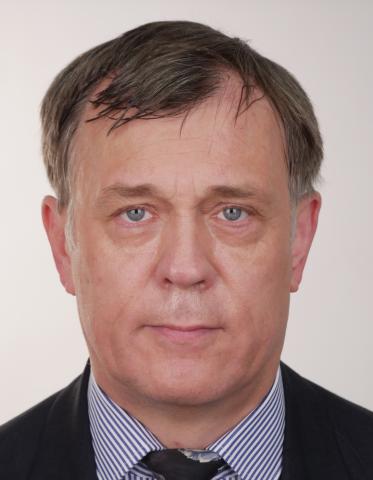 Causian man looks directly into camera, against a cream background