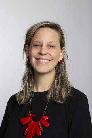 Woman wearing a black shirt and red necklace smile into the camera