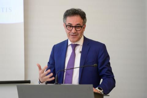 Man wearing a blur suit and glasses stands at a podium