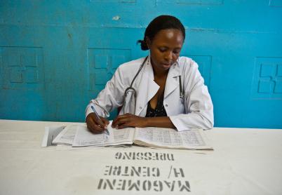 African woman wearing a white lab coat looks down at paperwork