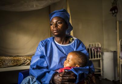 Health worker in scrubs holding a child