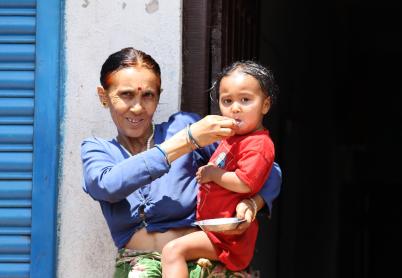 Grandmother holds child and spoon feeds her