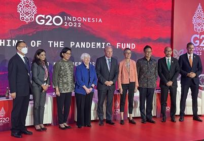 9 people in dress clothes stand on a stage, with a backdrop behind them that reads G20 Indonesia 2022, Launching of the Pandemic Fund