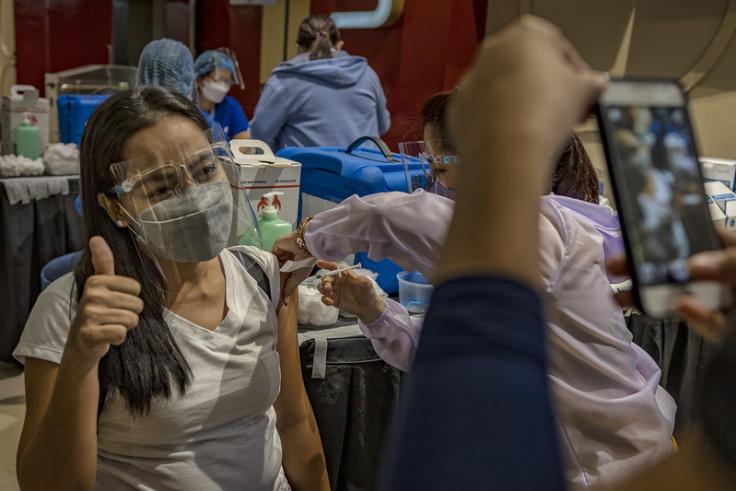 A woman gestures as she has her picture taken while receiving a dose of Moderna Covid-19 vaccine at a mall theatre on September 16, 2021 in Bacoor, Cavite province, Philippines. 