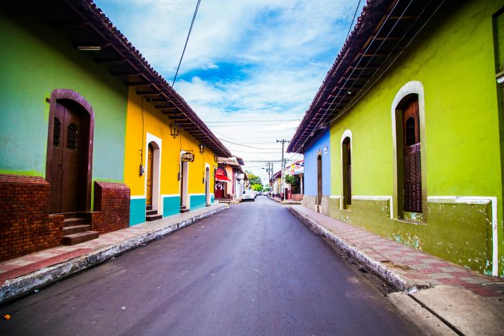 street of colorful houses (green, blue, yellow) under blue clouds during daytime