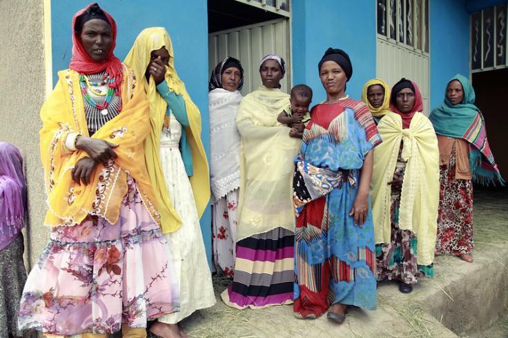 Women in rural village, in traditional and color dresses, two women are holding children in Ethiopia