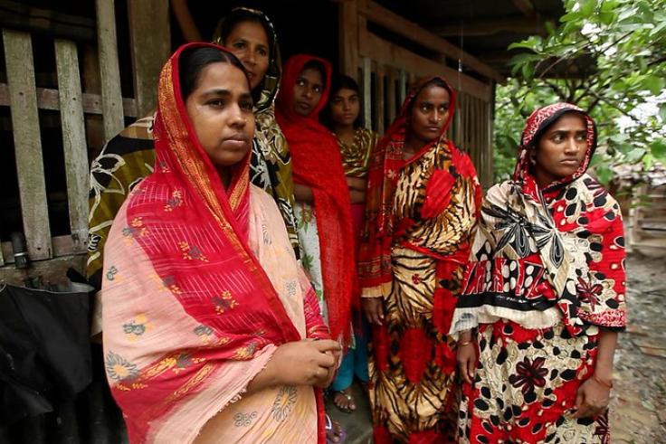 Women in rural village, southern Bangladesh, wearing traditional red and white dresses