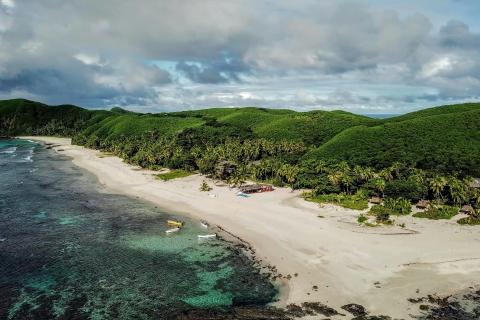 Blue water, sandy beach, green rolling hills in Fiji